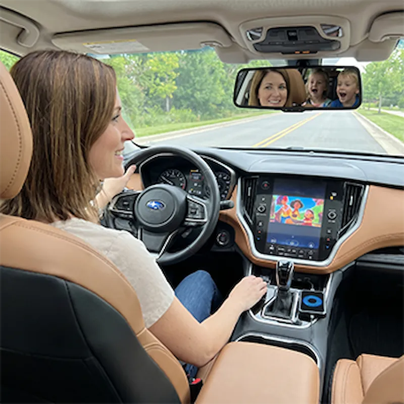 Frau fährt ruhig während Kinder auf dem Autobildschirm schauen via Roadcast