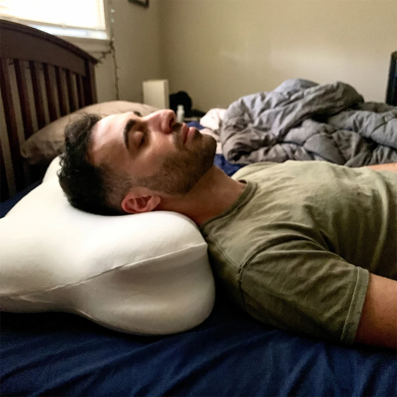 Mann schläft auf dem Rücken auf dem CloudNest Memory-Foam-Kissen